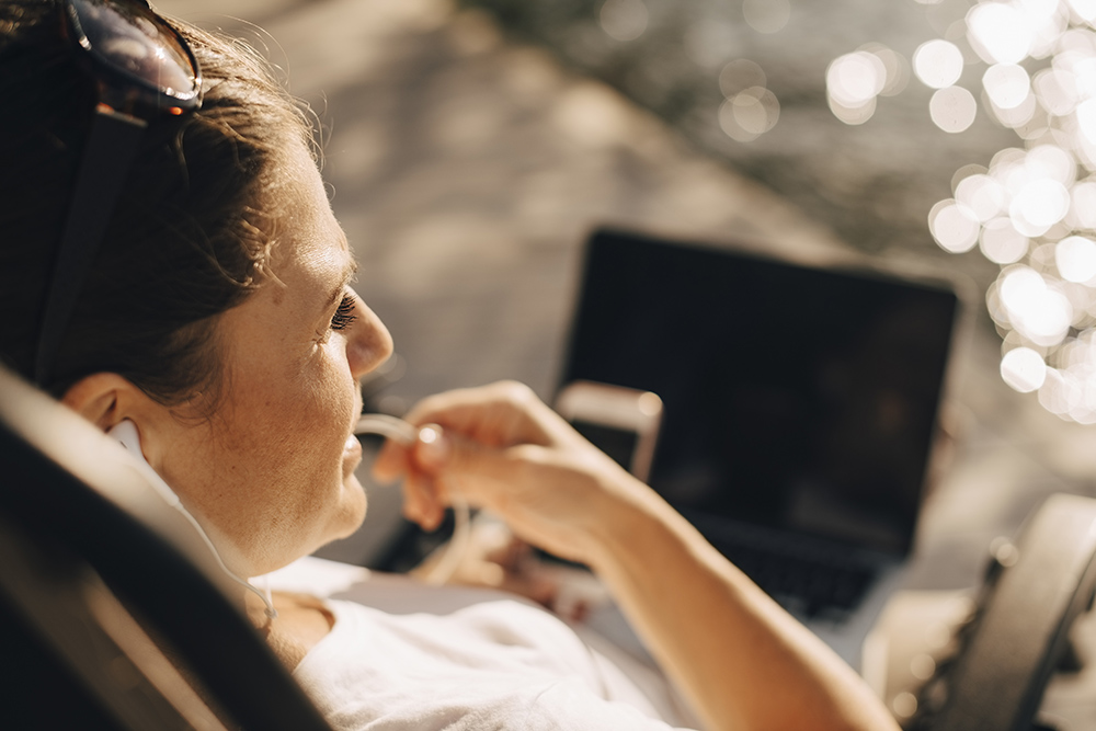 Kvinna sittande utomhus med en laptop i knät.