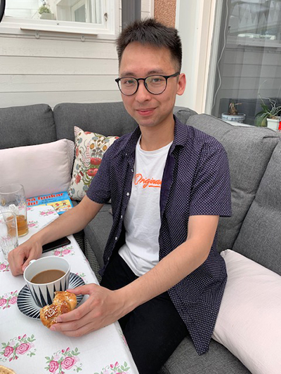 Mo Chen is sitting on a sofa with a cup of coffee in front of him.