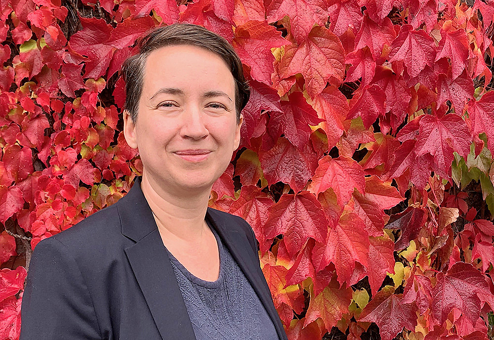 Rosa Lönneborg in front of a wall of red autumn leaves.