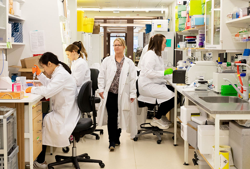 Professor Cecilia Williams walking in her laboratory at SciLifeLab, Solna. Doctoral students are working in the laboratory.