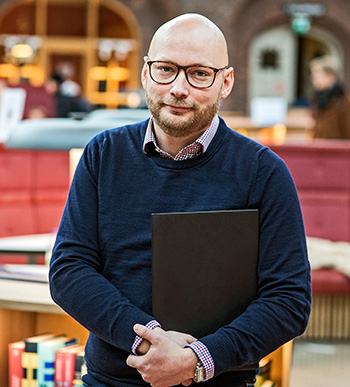 Stefan Stenbom i KTH:s bibliotek med en laptop i famnen.